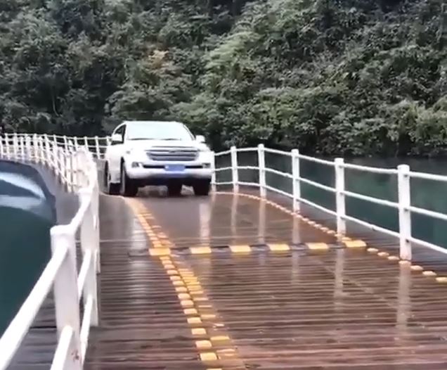 中国湖北省の水上に浮かぶ橋をたわませながら進む車